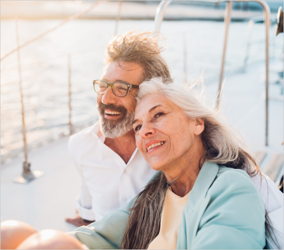 mature couple smiling and sitting on sail boat